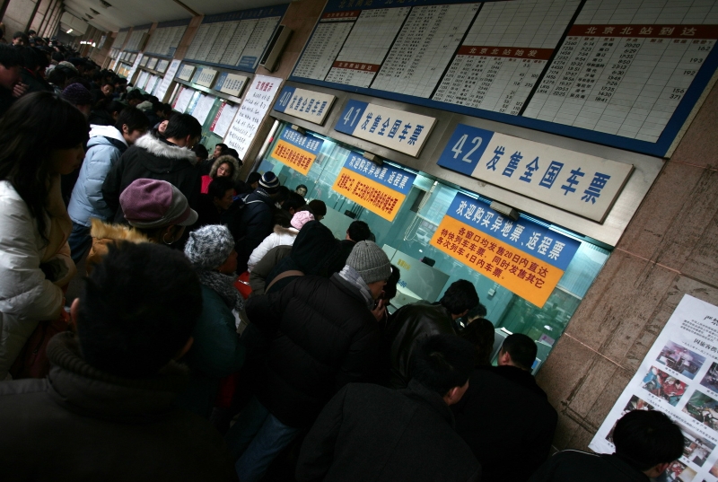 二十年前，春运买票意味着彻夜排队，图为2006年北京站售票窗口前买票的人们。摄影记者/王晓东